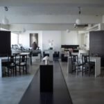 Sanctuary, Mapo: A Cathedral Built for Rest Sanctuary Mapo cafe interior in a minimalist black-and-white palette with concrete ceilings, white tables, cross-back chairs, globe lights, and curated shelves.